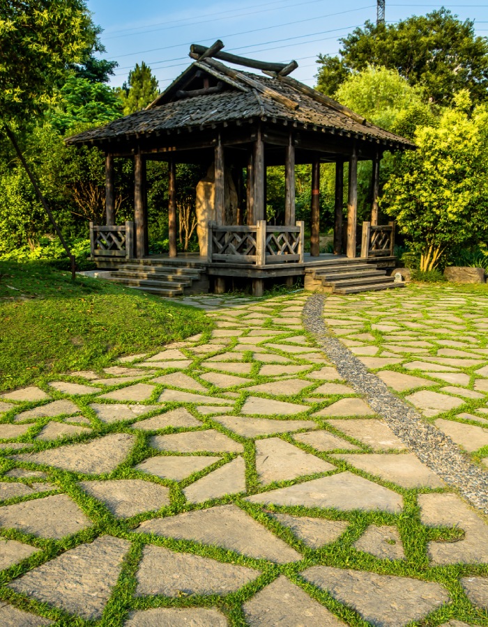 Allée en pierre naturelle dans un jardin avec pavillon en bois